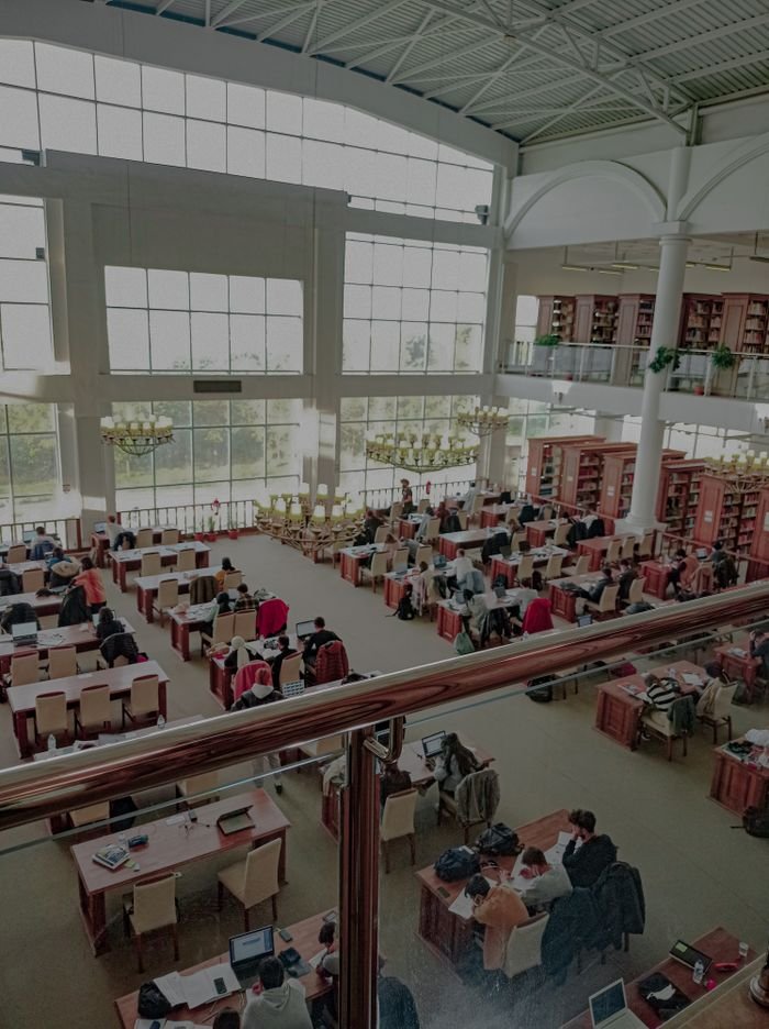 A bustling library in Çanakkale, Turkey, filled with students studying under natural light.